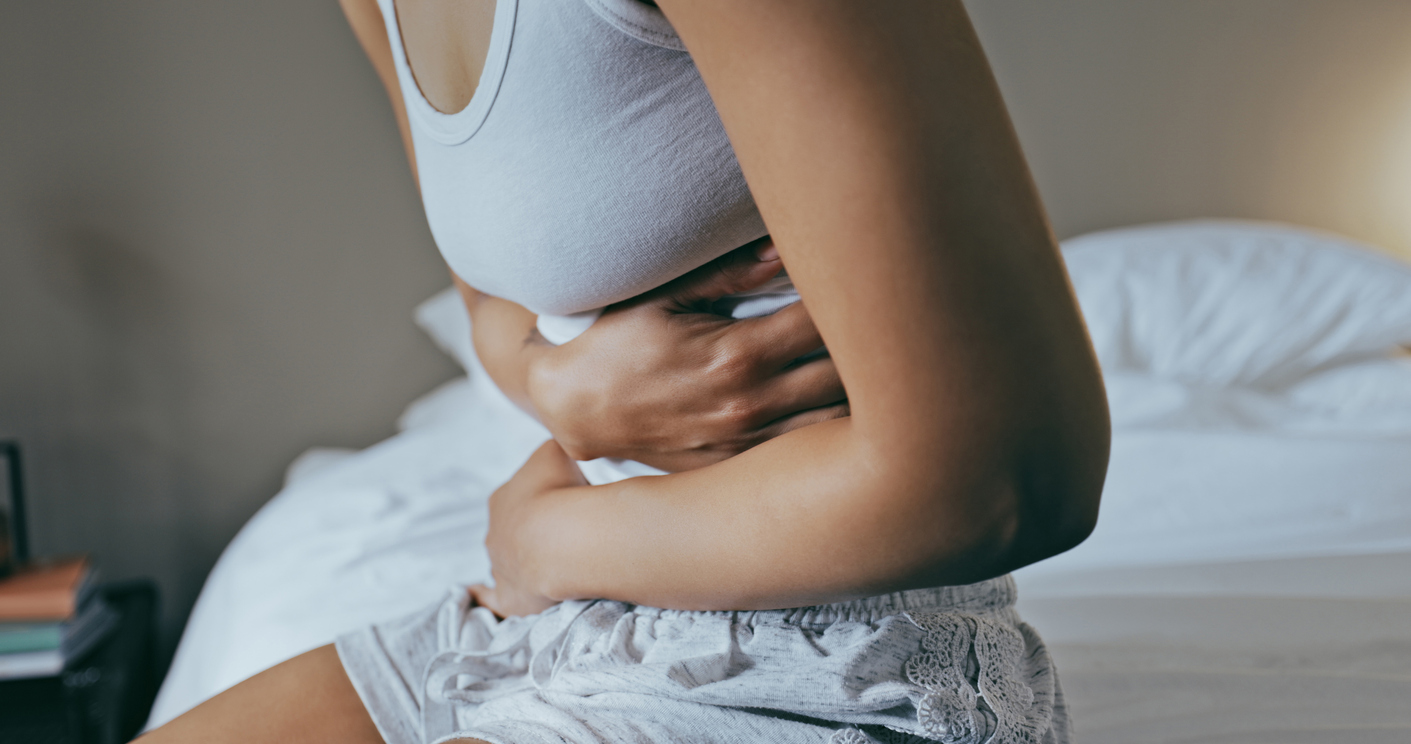 woman in bed holding her stomach in pain
